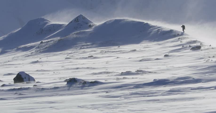A hiker walks on a snowy ridge in the wilderness
