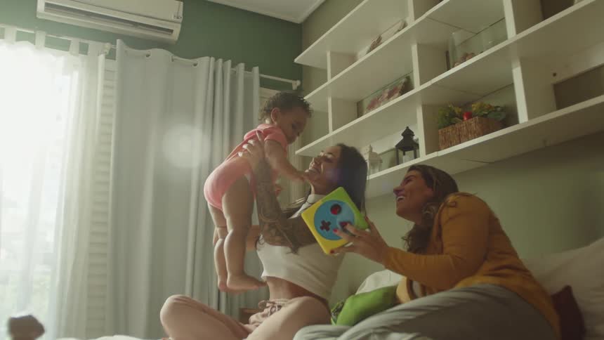 Two women playing with a child in bed