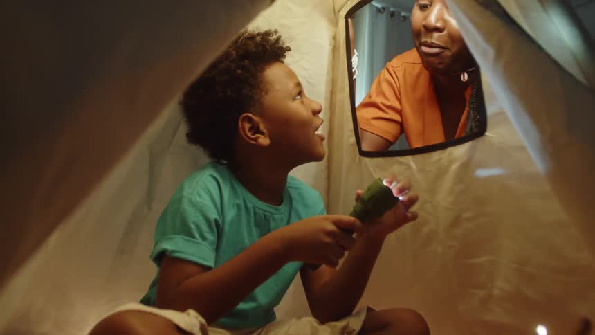 A mother is talking with her son who is holding a flashlight