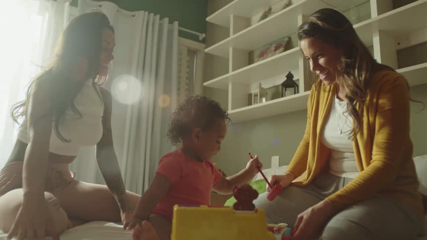 A girl is swinging a toy as her parents watch