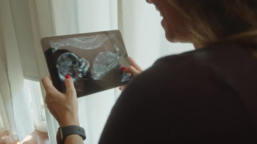 A woman zooms in on an ultrasound picture on her tablet