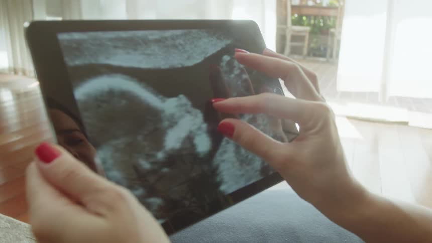 Woman smiles while looking at an ultrasound picture on a tablet