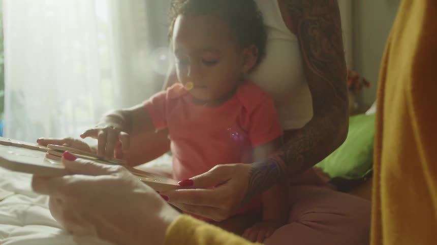 Daughter sitting in moms lap playing with a toy
