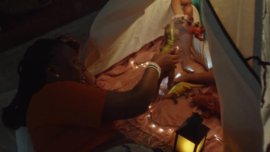 Mother playing with her little son who is in a makeshift tent in the living room