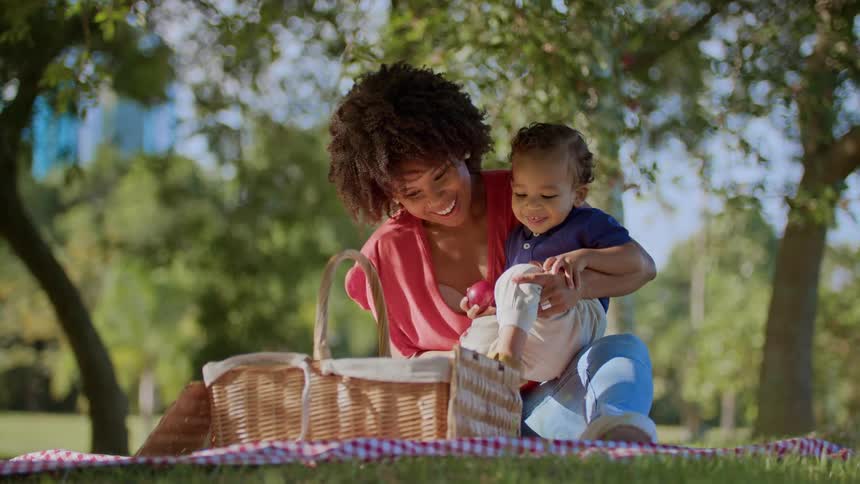Mother playing with her little son in a garden with a picnic