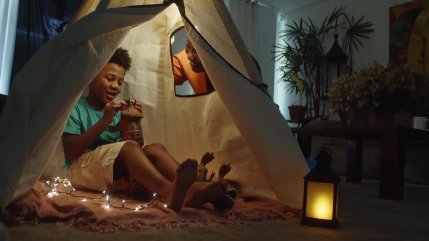 Boy playing in a makeshift tent with his mother by his side
