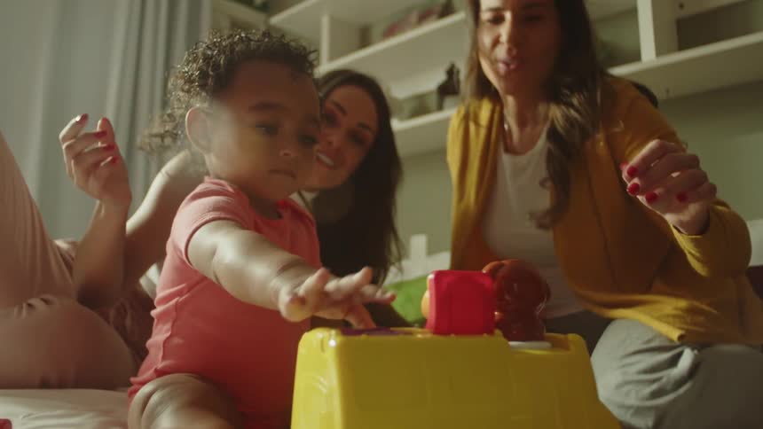 A mother watches her daughter play with a toy