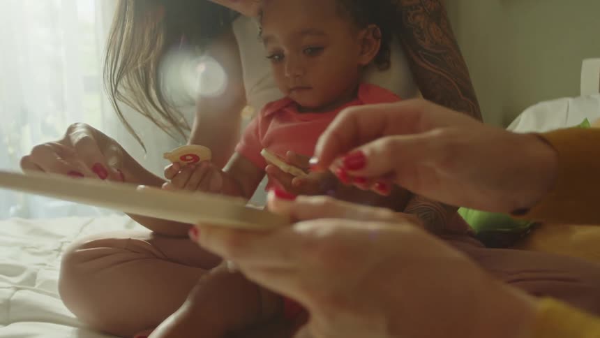Mother and daughter play with toys on the bed
