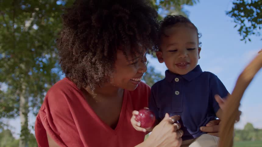 A boy laughs at a picnic with his mom