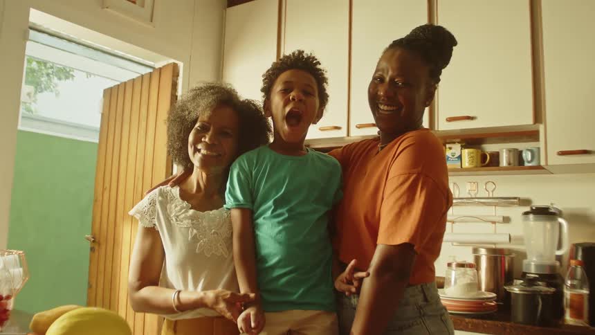 Little son with his grandmother and mother in the kitchen
