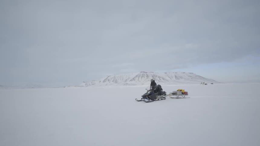 A person drives a snowmobile