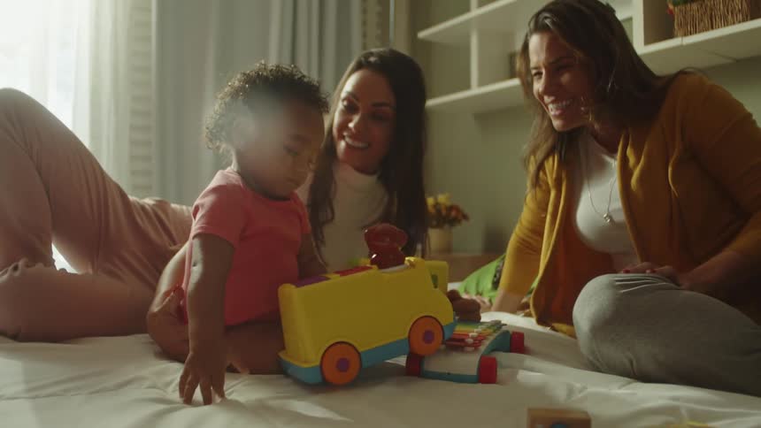 The girl is playing with a toy vehicle as her parents watch