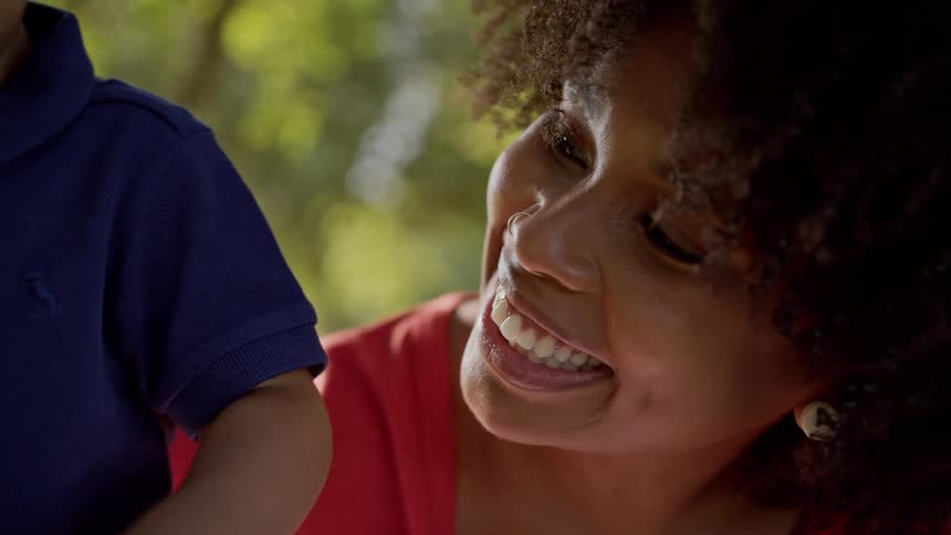 A woman smiles warmly while interacting with a child