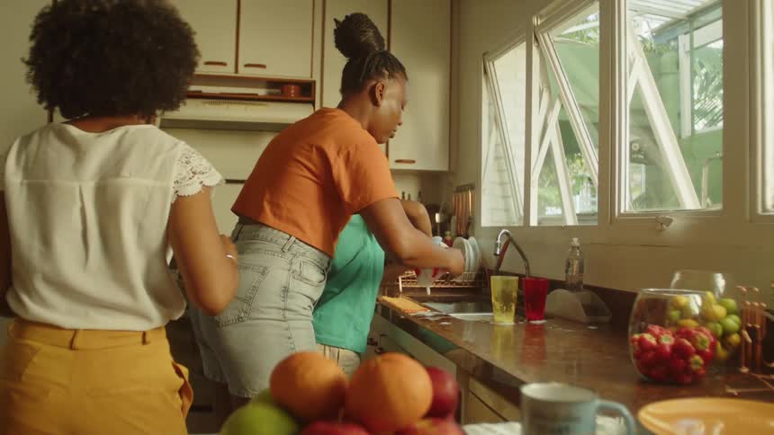 Two women in a kitchen with a boy washing dishes