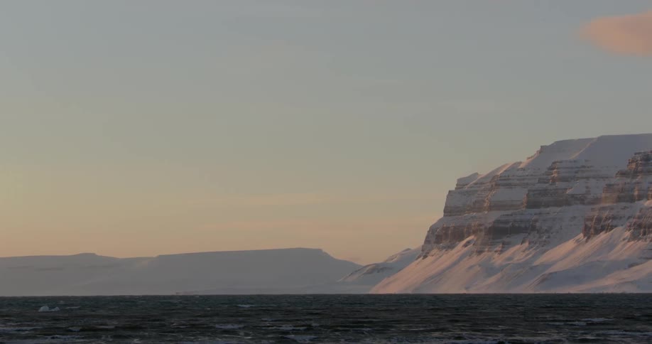 The sea meets the shore of snow-covered cliffs