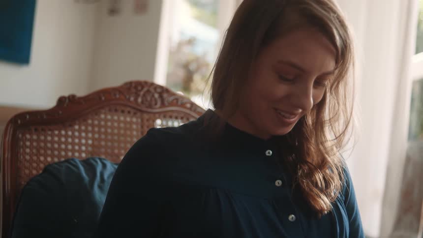 A pregnant woman touching her stomach smiles