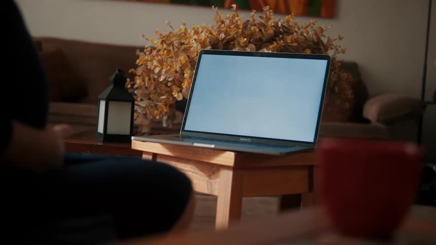 A person sitting in front of a laptop computer that is on a table in a living room