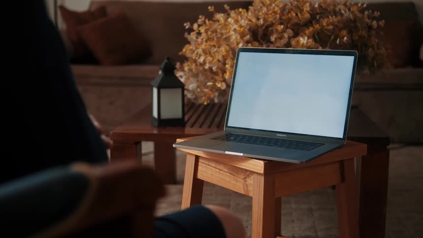 Open laptop on a wooden chair facing a person