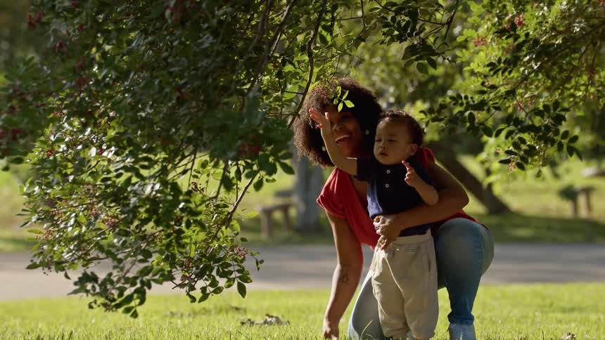 Mother with her little son under a tree with small fruits