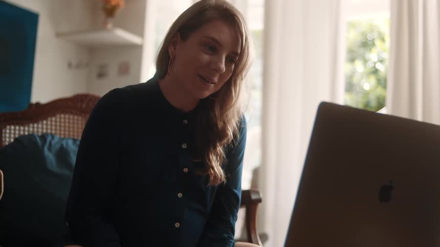 The woman is talking on a video call on the laptop