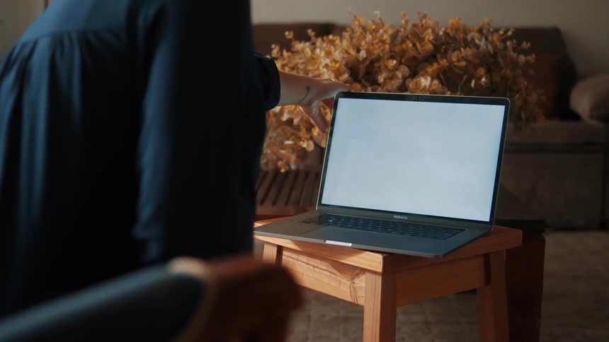 Womans hand adjusting a laptop screen in front of her