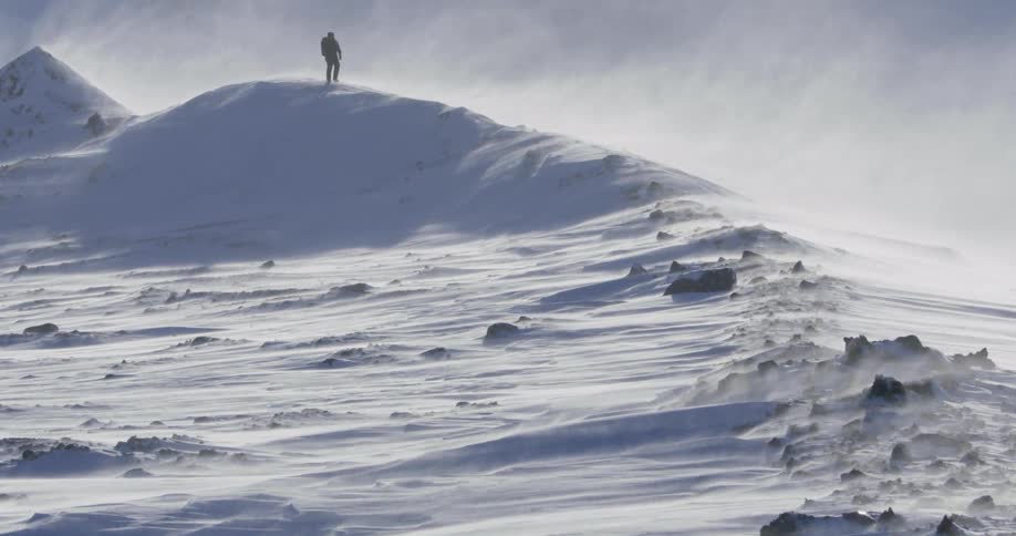 Snow blows across the air as a man treks through it