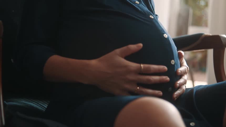 A woman is massaging her pregnant stomach