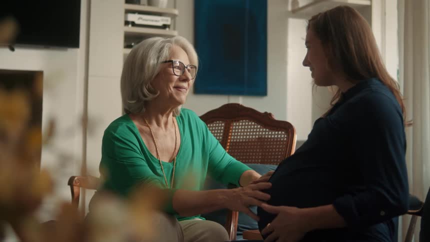 Older woman touches pregnant womans belly in a warm moment