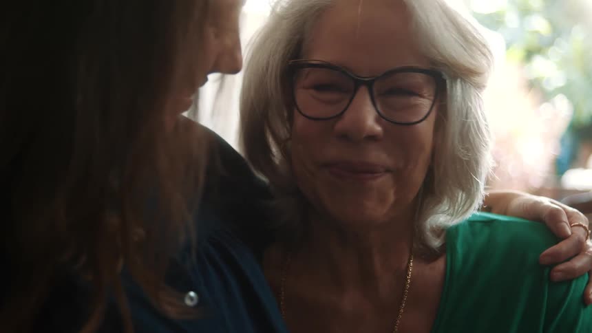 Older woman and her daughter smile while the younger woman hugs her mother