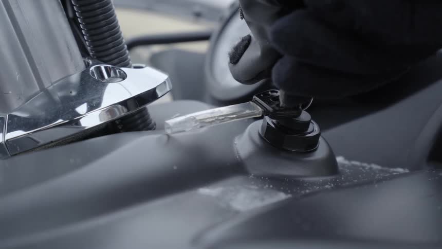 A person turns the key in a snowmobile