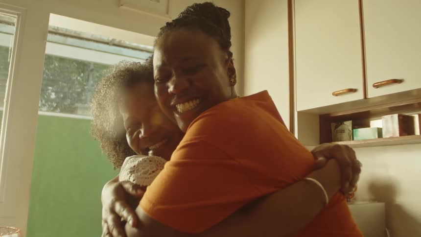 A mother and daughter are hugging in the kitchen