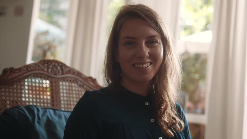 Woman raises her head and smiles while sitting in a living room