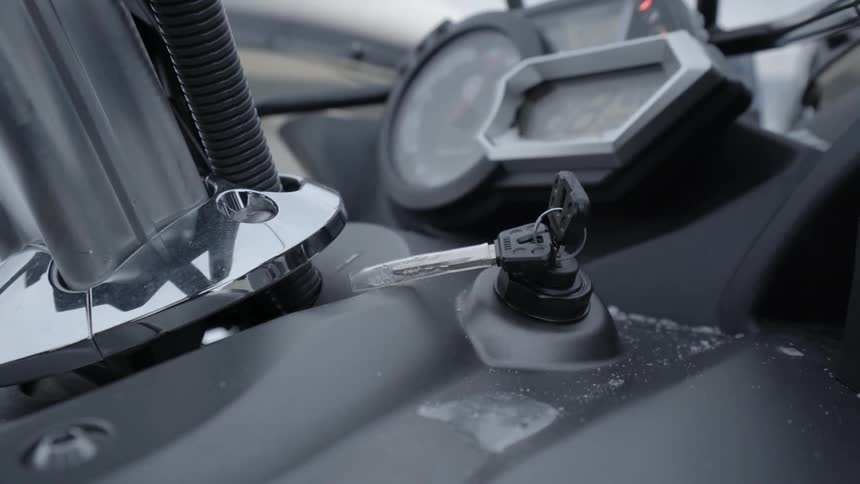 A person turns the key in a snowmobile