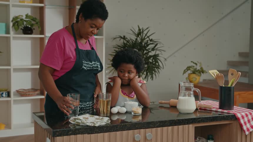 A woman and a young girl prepare ingredients together in a modern kitchen