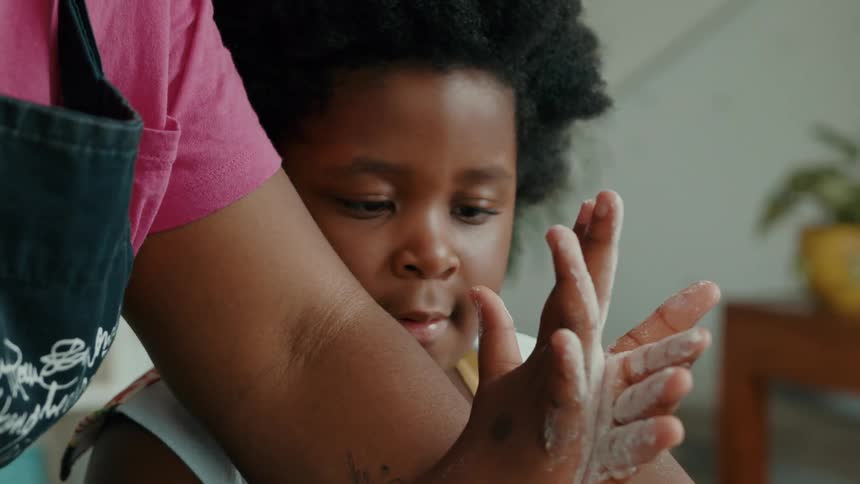 A girl picks up some flour from the counter