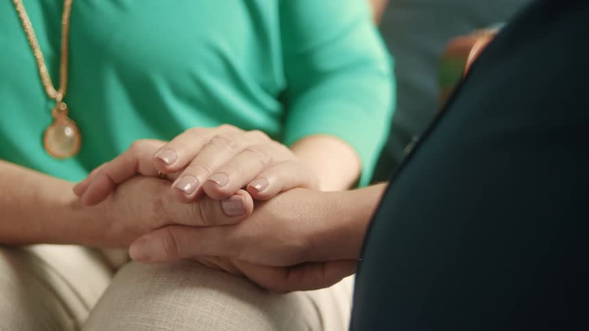 Pregnant womans hand clasped with another persons hand
