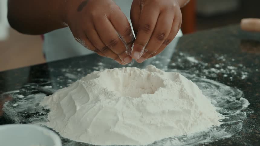 The girl sprinkles flour in the kitchen