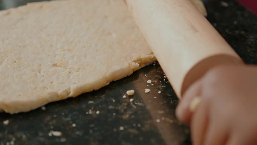 A person is pushing a rolling pin over the dough