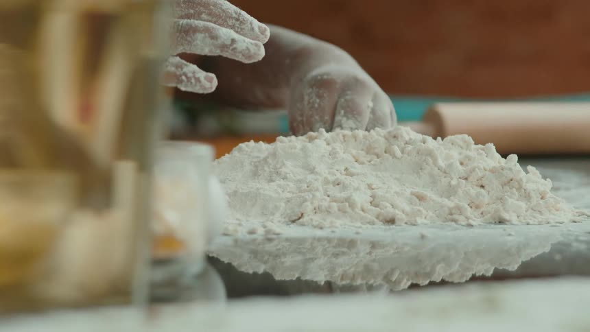 Two people are making something with a dough the camera is primarily focused on one persons hands