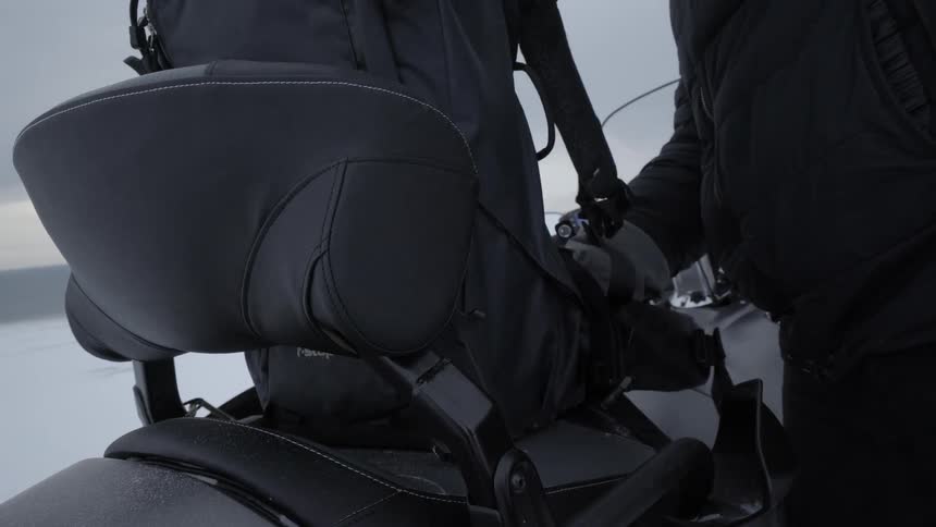 A person attaches a bag to a snowmobile