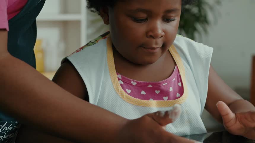 A girl pushes the flour into a pile