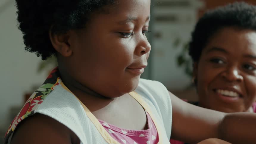 A mother watches her daughter as she touches the flour