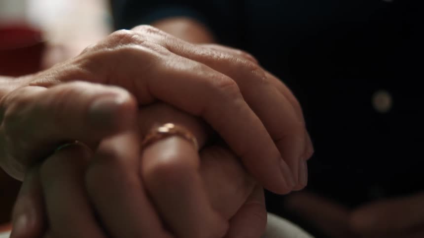 One person gently holds anothers hand conveying comfort and support