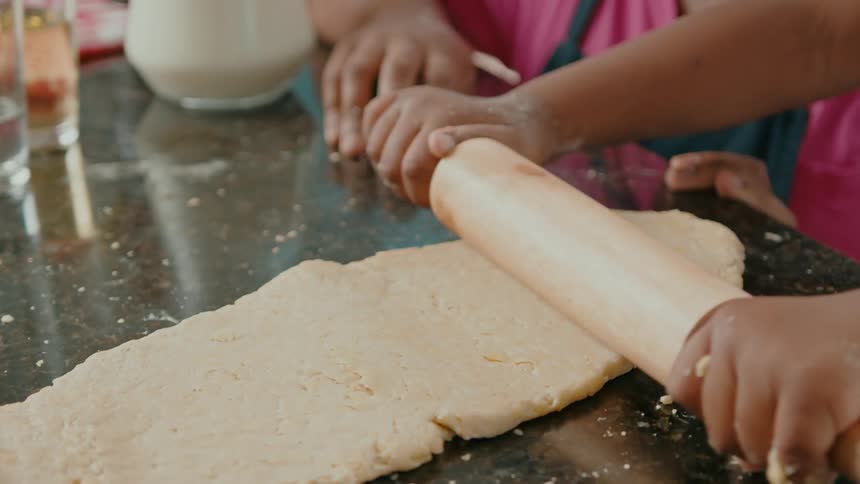 A child rolling out dough on a countertop