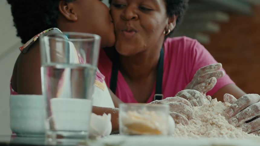 A woman and child share a loving moment while baking together at a kitchen table