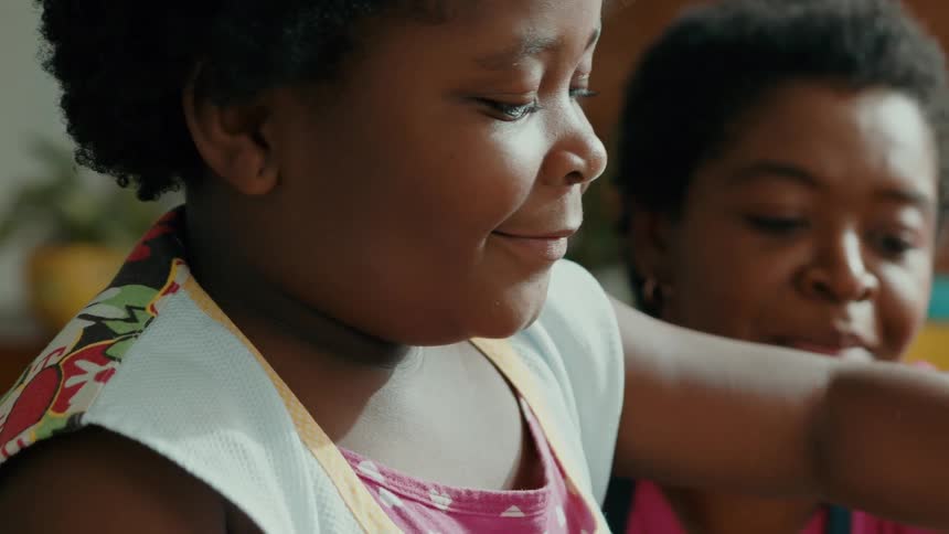 A child has a fun time indoors with their mother by their side both smiling and enjoying themselves at midday