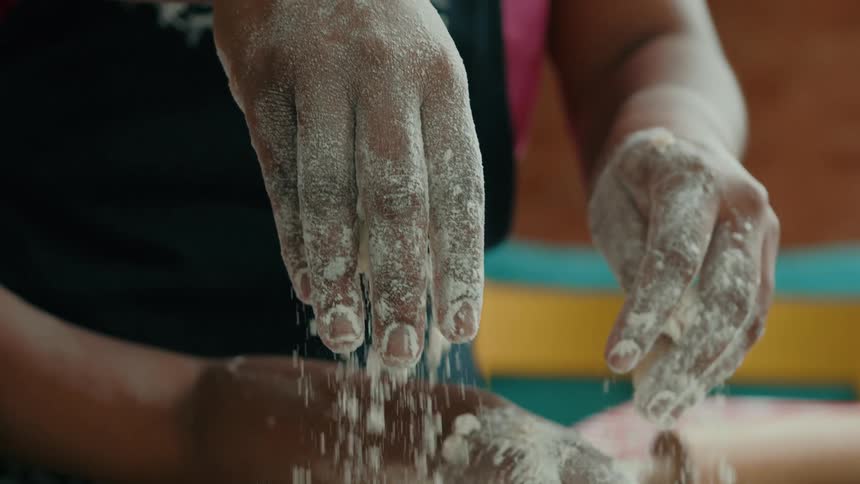 Flourdusted hands knead dough on a countertop scattered with baking tools and ingredients