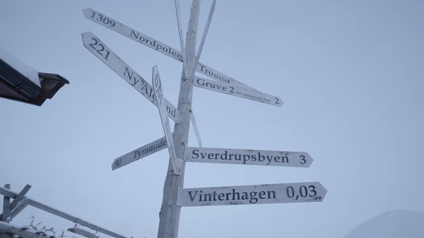 Town signs hang from a post pointing in different directions