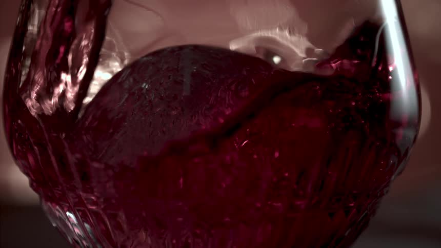 Wine pouring into a glass with a large ice sphere inside