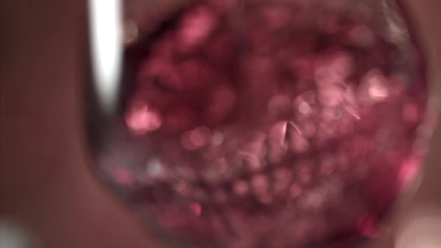 Close up of a red drink in a glass cup stirred as the cup is spun in a circular motion